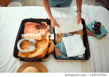 Travel packing, above and hands of a woman with clothes, holiday luggage and prepare for international summer. Suitcase, ready and person traveling with a suitcase, vacation clothing and hotel bag 129716794