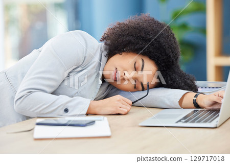 Black woman, sleeping and office desk while tired, burnout and fatigue while asleep by laptop at corporate company, head on table to relax. Lazy entrepreneur exhausted and sleepy due to work stress Black woman, sleeping and office desk while tired, burnout and fatigue while asleep by laptop at corporate company, head on table to relax. Lazy entrepreneur exhausted and sleepy due to work stress 129717018
