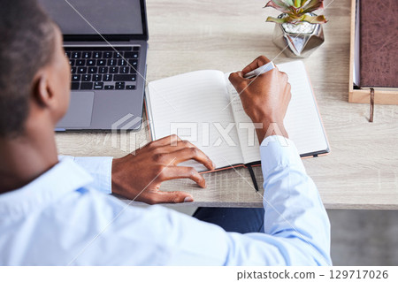 Businessman, writing in notebook and planning corporate schedule, calendar and brainstorming idea for lead generation. Black man, write contact list in book and working on advertising strategy goal 129717026
