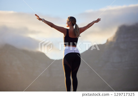 Freedom, fitness and woman in nature by mountain spreading hands wide open. Open arms, peace and female relax outdoors on break enjoying view after running, exercise or training, hike or workout. 129717325