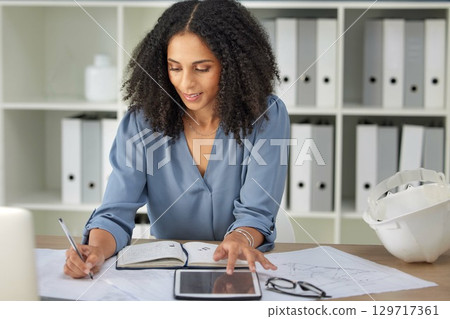 Architecture, engineering and woman with blueprints writing notes on tablet and notebook in office. Strategy, planning and design, black woman architect working on building plans and online documents Architecture, engineering and woman with blueprints writing notes on tablet and notebook in office. Strategy, planning and design, black woman architect working on building plans and online documents 129717361
