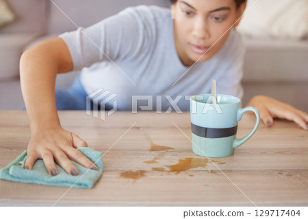 Cleaning surface, coffee spill and woman wipe furniture, coffee table and counter in living room with cloth. Housekeeping, hygiene and young woman with rag for liquid mess, dirt and stain from tea 129717404