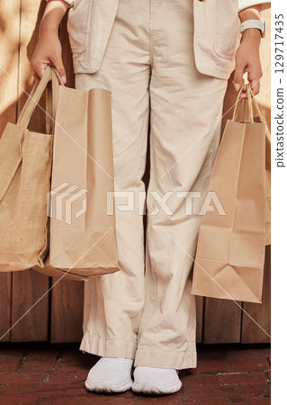 Sustainability, fashion paper bag and woman legs for eco friendly, vegan and designer retail clothes in shopping, commerce and economy. Sustainable market, sale and discount of customer bag in hands 129717435