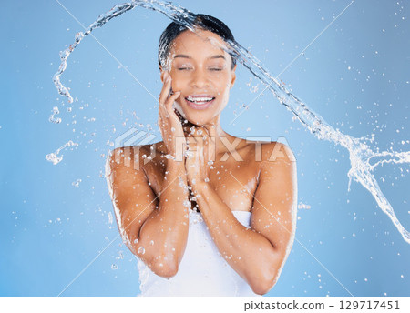 Happy black woman, water splash or showering in skincare grooming, healthcare or sustainability cleaning on isolated blue background. Zoom, smile or beauty model in wet drops or hydration dermatology Happy black woman, water splash or showering in skincare grooming, healthcare or sustainability cleaning on isolated blue background. Zoom, smile or beauty model in wet drops or hydration dermatology 129717451