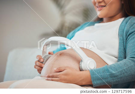 Pregnant woman, headphones and listening to music or podcast for zen, calm and peace with hands on stomach for kick and moving. Female with wireless audio to relax and connect during pregnancy 129717596