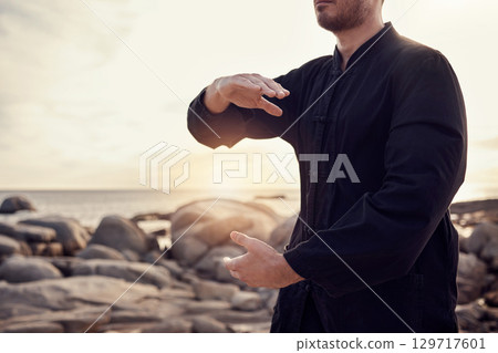 Beach, peace and tai chi, man in nature for balance and peace for mental wellness or control of body and mind. Spiritual health, fitness and meditation, energy and self care on rocks at sea in sunset 129717601