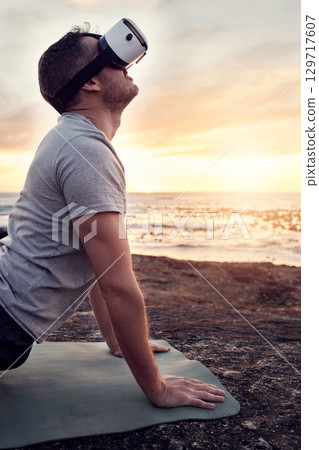 VR, yoga and man stretch on the beach for fitness, flexibility and health and wellness at sunset. Metaverse, ai and futuristic male yogi with a headset and yoga mat for training and ocean pilates VR, yoga and man stretch on the beach for fitness, flexibility and health and wellness at sunset. Metaverse, ai and futuristic male yogi with a headset and yoga mat for training and ocean pilates 129717607