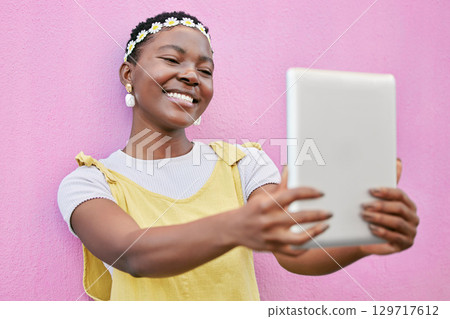 Black woman, selfie or tablet for smile, flower crown or happiness by pink wall in spring on social media. Happy influencer woman, digital photo and head flowers in fashion, beauty or social network Black woman, selfie or tablet for smile, flower crown or happiness by pink wall in spring on social media. Happy influencer woman, digital photo and head flowers in fashion, beauty or social network 129717612