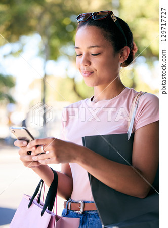 Woman, shopping and phone with bags in ecommerce, online banking or texting in the nature outdoors. Female shopper with smile chatting, online shopping or internet banking for communication outside Woman, shopping and phone with bags in ecommerce, online banking or texting in the nature outdoors. Female shopper with smile chatting, online shopping or internet banking for communication outside 129717727