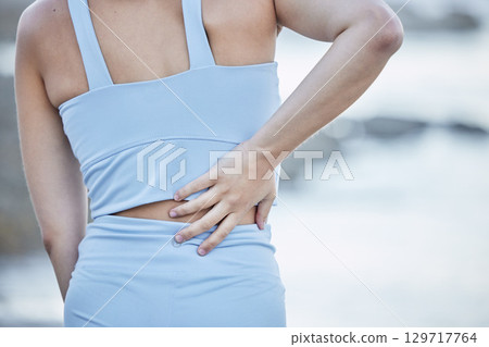 Woman runner, back pain and hand for massage, physical therapy or self care at outdoor training. Girl, lower back injury and nature workout for health, fitness and wellness in summer morning at beach Woman runner, back pain and hand for massage, physical therapy or self care at outdoor training. Girl, lower back injury and nature workout for health, fitness and wellness in summer morning at beach 129717764