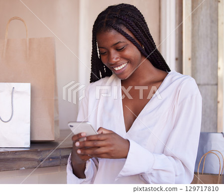 Black woman, smartphone and shopping, happy and communication, retail and sale with bargain, discount with technology. Phone, shopping bag in mall and social media, text message and mobile app. 129717810