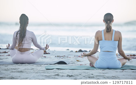 Beach, wellness and friends doing a yoga exercise for outdoor mind, body and spiritual wellness. Zen, lotus pose and peaceful women doing a pilates or meditation workout together in nature by ocean. Beach, wellness and friends doing a yoga exercise for outdoor mind, body and spiritual wellness. Zen, lotus pose and peaceful women doing a pilates or meditation workout together in nature by ocean. 129717811