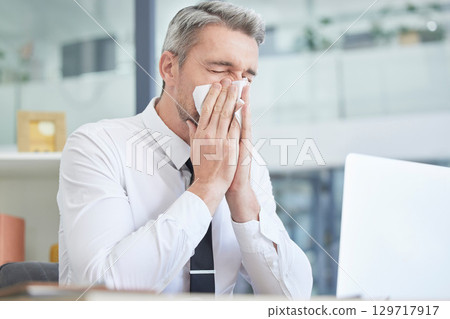 Allergies, sick and businessman in his office cleaning nose with healthcare risk, workplace compliance policy and management stress. Dust, bacteria and allergy of business or corporate man at a desk 129717917