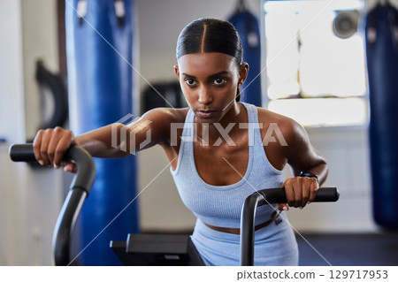 Cycling, gym bicycle and woman focus on fitness performance, air bike workout or cardio training for strong body health. Wellness motivation, machine and serious girl working on exercise challenge Cycling, gym bicycle and woman focus on fitness performance, air bike workout or cardio training for strong body health. Wellness motivation, machine and serious girl working on exercise challenge 129717953