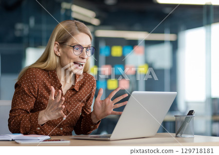 Successful businesswoman at workplace celebrating successful achievement results. Woman received online notification of winning and triumphant results of new project. 129718181
