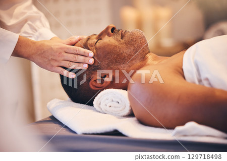 Hands, head and massage with a man in a spa on a bed or table for wellness, luxury or stress relief treatment. Relax, zen and beauty with a male customer lying in a health center for physical therapy 129718498