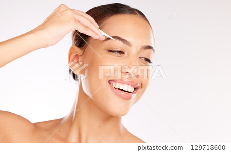 Woman, face or tweezer for eyebrow shape, hair growth management or self care grooming on studio background. Smile, happy or beauty model with hair removal tool for microblading treatment or skincare Woman, face or tweezer for eyebrow shape, hair growth management or self care grooming on studio background. Smile, happy or beauty model with hair removal tool for microblading treatment or skincare 129718600