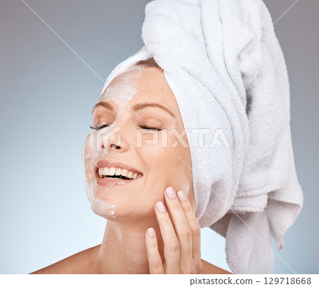 Skincare, cream and woman from the shower, happy cleaning and marketing beauty against a grey studio background. Spa smile, face mask and model with application of sunscreen for body care and health 129718668