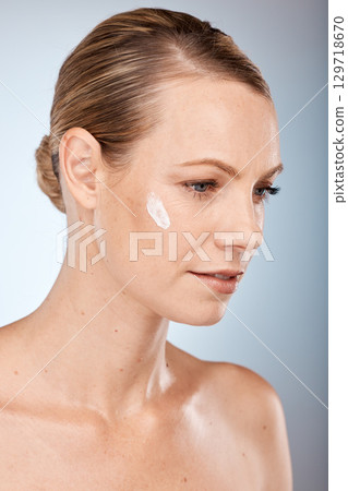 Beauty, woman and thinking with skincare cream on face for body care, health and cosmetic treatment. Natural, sunscreen and wellness cosmetics model with idea about skin creme in gray studio. 129718670