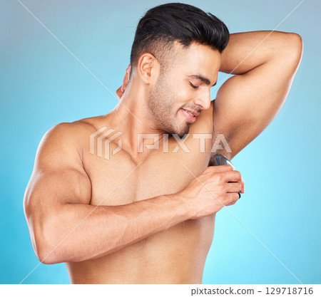 Grooming, armpit and man shaving body hair for hygiene, health and wellness on a blue studio background. Indian model for epilation with electric shaver for hair removal for clean underarm and skin Grooming, armpit and man shaving body hair for hygiene, health and wellness on a blue studio background. Indian model for epilation with electric shaver for hair removal for clean underarm and skin 129718716