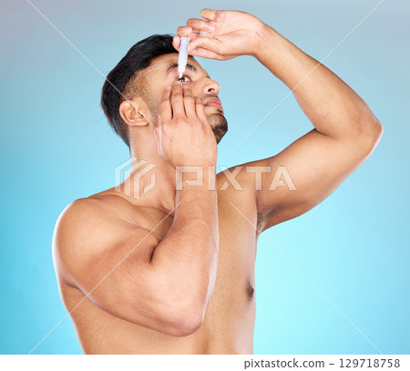 Man, eye drops and vision in studio for healthcare, eyesight and medical product for allergies. Shirtless model, liquid solution and eyes to stop allergy, self care and wellness by blue background 129718758