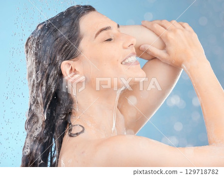 Shower, cleaning and woman with water for hair in studio for skincare, body care and wellness on blue background. Self care, hydration and girl washing with shampoo, conditioner and hair products 129718782