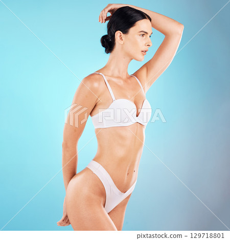 Wellness, fitness and woman with slim body in studio on blue background for nutrition, diet and body care. Healthcare, self care and girl torso in underwear pose for beauty, exercise and weight loss 129718801