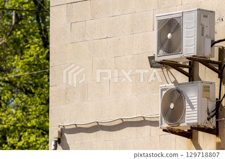 air conditioner on wall of an apartment building with view of green trees. air conditioner on wall of an apartment building with view of green trees. 129718807