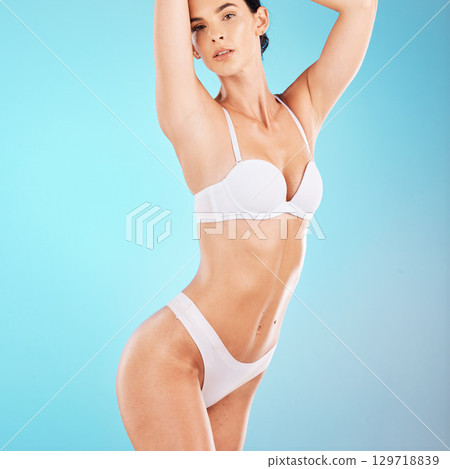 Woman in underwear, body and wellness on blue background for healthy lifestyle, skincare and wellness in studio. Portrait of young model in lingerie, beauty and weightloss diet for stomach gut health Woman in underwear, body and wellness on blue background for healthy lifestyle, skincare and wellness in studio. Portrait of young model in lingerie, beauty and weightloss diet for stomach gut health 129718839