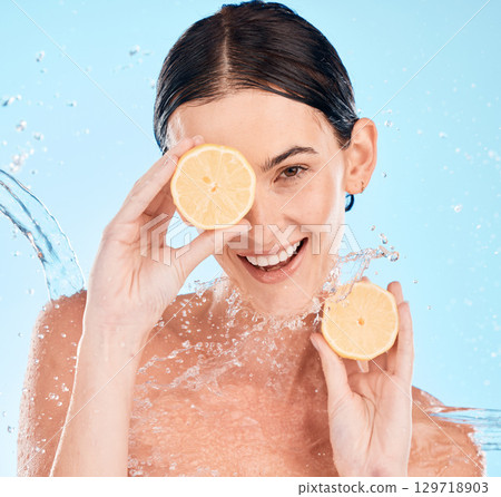 Water splash, lemon and portrait of woman in studio for an organic, natural and healthy skincare treatment. Vitamin c, beauty and model with citrus fruit for face and skin wellness by blue background Water splash, lemon and portrait of woman in studio for an organic, natural and healthy skincare treatment. Vitamin c, beauty and model with citrus fruit for face and skin wellness by blue background 129718903
