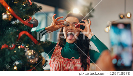 Christmas tree, funny and picture with woman and ornament for festive season, memory and decoration. Merry xmas, holiday and photography with silly person in living room of home for happy and bauble Christmas tree, funny and picture with woman and ornament for festive season, memory and decoration. Merry xmas, holiday and photography with silly person in living room of home for happy and bauble 129718978