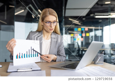 A professional woman in a modern office demonstrating business data analysis using a chart during a presentation or meeting. A professional woman in a modern office demonstrating business data analysis using a chart during a presentation or meeting. 129719038