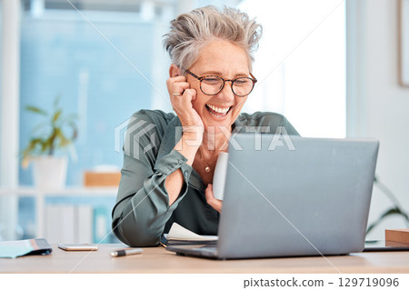 Laptop, coffee and senior business woman laughing at an email in her office at work for fun or humor. Computer, tea and comic with a mature female employee working on a report or project and joking 129719096