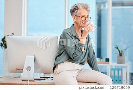 Happy, coffee and glasses with a female leader, CEO or manager drinking a beverage in a work office. Thinking, management and corporate with a senior business woman sitting on a desk while working 129719099