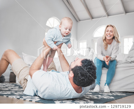 Family, baby and playful with a father and daughter having fun in the living room with mom sitting on the sofa. Love, floor and happy with a man, girl and woman bonding together in their home 129719129
