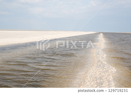 Landscape of a salt lake with a flat white surface under the light of a blue sky. Lake Baskunchak in the Astrakhan region of Russia. Landscape of a salt lake with a flat white surface under the light of a blue sky. Lake Baskunchak in the Astrakhan region of Russia. 129719231