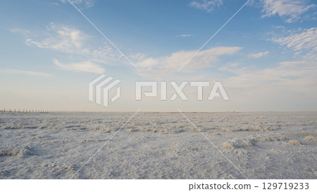 Landscape of a salt lake with a flat white surface under the light of a blue sky. Lake Baskunchak in the Astrakhan region of Russia. 129719233