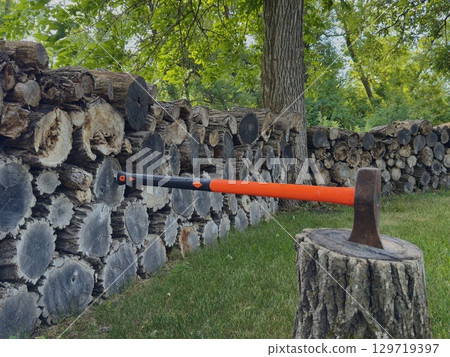 Axe in stump with stacked firewood Axe in stump with stacked firewood 129719397