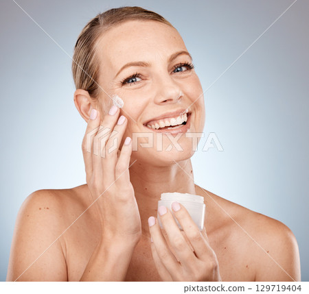 Skincare, beauty and face of woman with cream, smile and happiness for cosmetics, makeup and dermatology treatment on grey studio background. Portrait of Canada model do self care for skin with glow Skincare, beauty and face of woman with cream, smile and happiness for cosmetics, makeup and dermatology treatment on grey studio background. Portrait of Canada model do self care for skin with glow 129719404
