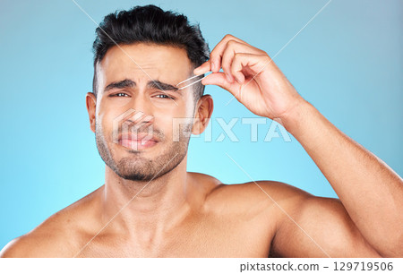 Beauty, grooming and eyebrow with man and tweezers for self care, hair removal and facial. Pain, focus and shape with model and plucking for cosmetics, treatment and cleaning in blue background 129719506