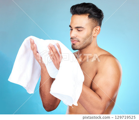 Towel, face and skincare for man, beauty and shower, personal hygiene and grooming cosmetics on studio blue background. Young guy, cotton cloth and facial cleaning for wellness, bath and self care 129719525