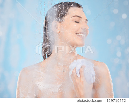 Water, soap and skincare with woman in shower for beauty, self care and hygiene routine. Relax, luxury and spa with girl model and sponge for cosmetics, salon or cleaning in blue background in studio 129719552
