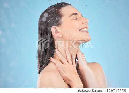 Woman shower, smile and studio with water, washing and cleaning for skincare, cosmetic health or wellness. Happy model, water drops or cosmetics for self care, skin or healthy body by blue background 129719558