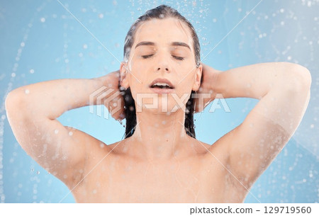 Water, woman and body shower on blue background for healthy skincare, beauty and wellness. Young studio model, water splash and washing hair for personal hygiene, self care and cleaning in bathroom Water, woman and body shower on blue background for healthy skincare, beauty and wellness. Young studio model, water splash and washing hair for personal hygiene, self care and cleaning in bathroom 129719560