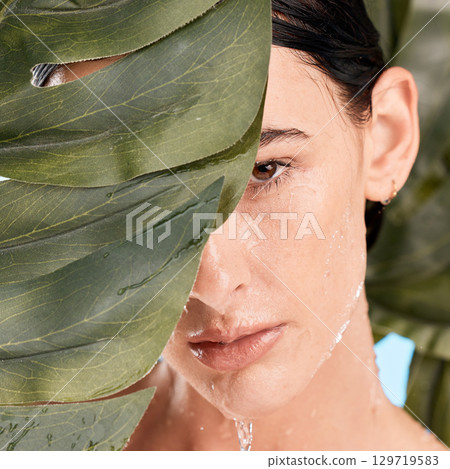 Woman, skincare and jungle leaves by face with water drop, moisturizer and wellness with mystery. Plants, natural cosmetic and water on model skin for health, organic cleaning and facial aesthetic 129719583