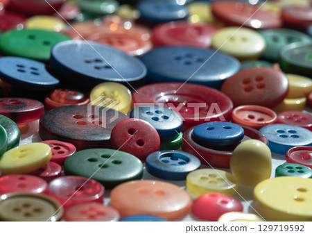 a close-up of a pile of colorful sewing buttons of various sizes and shades and patterns. Craft background, 129719592