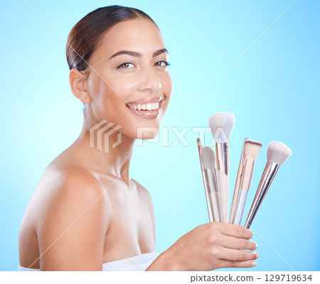 Skincare, beauty and makeup brush for portrait, cosmetics and foundation for glow, smile and happiness on face with blue studio background. Aesthetic Colombia model with beautician or makeover tools 129719634
