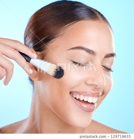 Woman, beauty and makeup brush in studio, smile and cosmetics for skincare, face and happiness. Happy black woman, model and cosmetic foundation for powder, glow and wellness by blue background 129719635