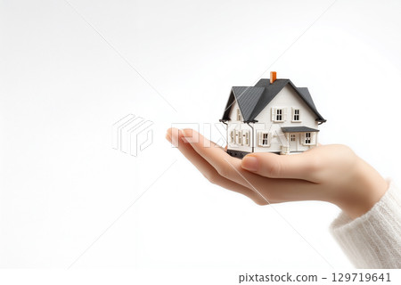 A woman's hand holding a house model. Image material for building a home 129719641