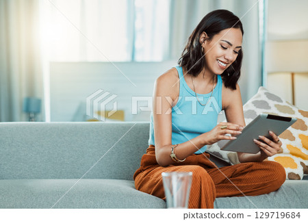 Streaming movies to watch online on digital tablet, watching videos and scrolling on social media while relaxing on the couch alone at home. Happy, smiling and casual female browsing the internet Streaming movies to watch online on digital tablet, watching videos and scrolling on social media while relaxing on the couch alone at home. Happy, smiling and casual female browsing the internet 129719684